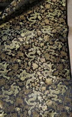 a black and gold brocaded fabric with animals on it