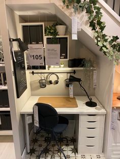 a desk with a chair underneath it in a room that has stairs and plants on the wall