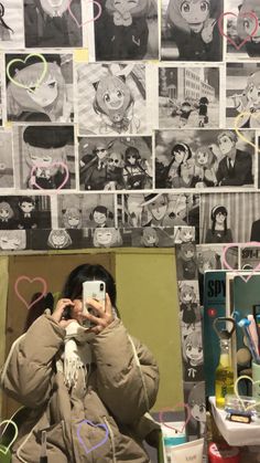 a person taking a selfie in front of a wall with pictures and hearts on it