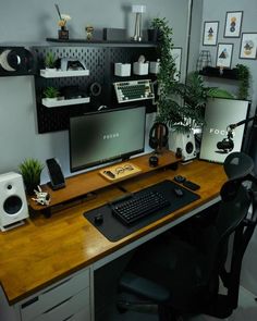 a desk with a keyboard, monitor and speakers on it next to a plant in a pot