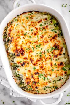 a casserole dish with broccoli, cheese and parsley in it