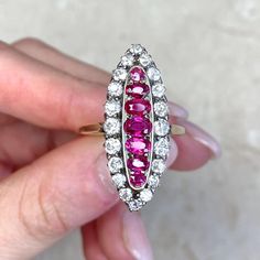 a woman's hand holding an old fashioned ring with pink and white stones on it