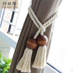 two wooden beads hanging from the side of a drapes in front of a window