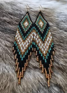 a pair of beaded earrings sitting on top of a fur