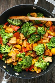 stir fry with broccoli, tofu and peppers in a skillet on a wooden table