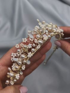 a woman is holding a tiara with pearls and other jewelry items on it's fingers