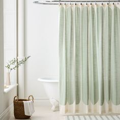 a white bath tub sitting next to a shower curtain with green and beige stripes on it