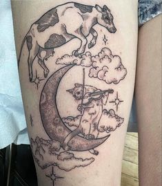 a woman's leg with a cow on the moon and clouds in the sky