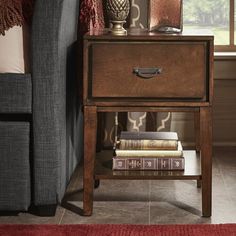 a night stand with two books on it next to a couch