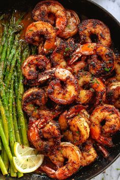 grilled shrimp and asparagus in a skillet with lemon wedges on the side