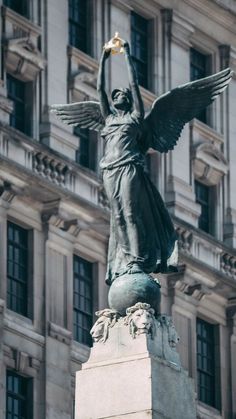 an angel statue on top of a pedestal in front of a tall building with many windows