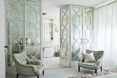 a living room filled with furniture and walls covered in frosted glass panels, along with curtains