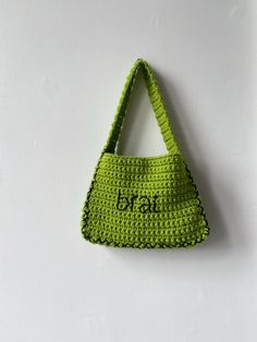 a crocheted bag hanging on the wall with it's name written in black