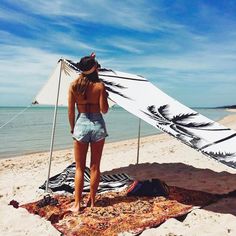 a woman standing on top of a sandy beach next to the ocean