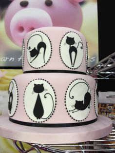 a three tiered cake decorated with black cats and a pink pig on the side