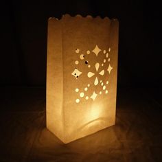 a paper bag that is lit up in the dark with stars and hearts on it