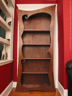 an empty bookcase in the corner of a room with red walls and white trim