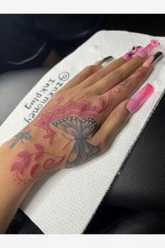 a woman's hand with pink and black tattoos on her left arm, resting on a white towel