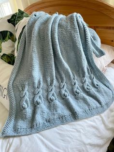 a blue knitted blanket sitting on top of a bed