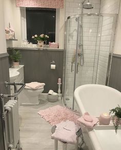 a white bath tub sitting next to a toilet and sink in a bathroom with pink rugs on the floor