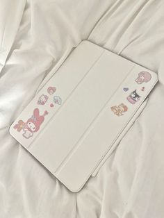 an open book with hello kitty stickers on it laying on a white bed sheet