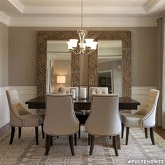 a dining room table with chairs and a chandelier hanging from the ceiling in front of a mirror