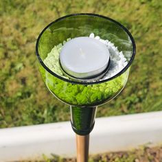 a candle that is sitting in some kind of glass bowl on top of a pole