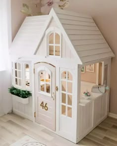 a white doll house sitting on top of a wooden floor