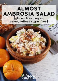 a bowl of salad next to three oranges on a white table with the words almost ambrosia salad written above it