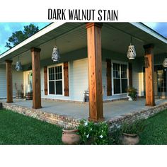 the front porch is covered with wooden pillars and hanging planters on either side of it