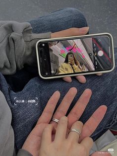 a person holding a cell phone in their lap and showing it to the camera with both hands