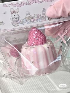 a pink cake in a clear box on a table