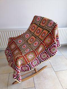 a chair with a blanket on it sitting in front of a radiator