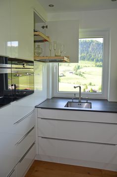 a kitchen with white cabinets, black counter tops and a window that looks out onto the countryside