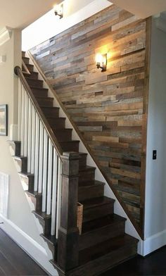 a wooden stair case next to a light on the wall in a room with hardwood floors