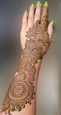 a woman's hand with henna tattoos on her left arm and green nails