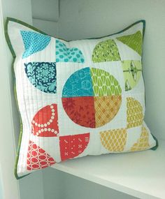 a colorful pillow sitting on top of a white shelf