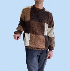 a man standing in front of a blue background wearing a brown and white knitted sweater