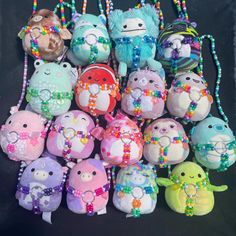 a bunch of stuffed animals that are on a black surface with beaded necklaces