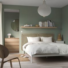 a bedroom with green walls, white bedding and wooden flooring is pictured in this image