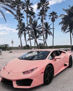 a pink sports car parked in front of palm trees