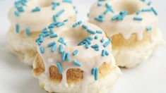 three donuts with white frosting and blue sprinkles