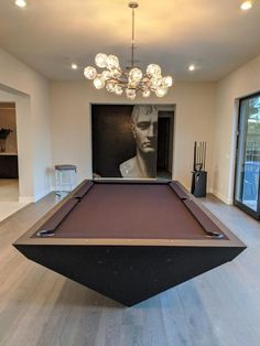 a pool table in the middle of a room with a chandelier above it