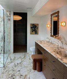 a bathroom with marble counter tops and two sinks, along with a walk in shower