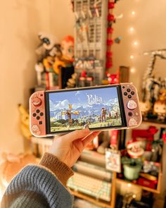 a person holding up a nintendo wii game controller in front of a room full of toys