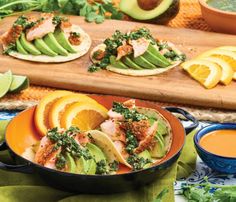 an orange and avocado dish is served on tortillas with sauces