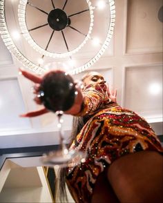 a woman with her face painted and holding a wine glass in front of a clock