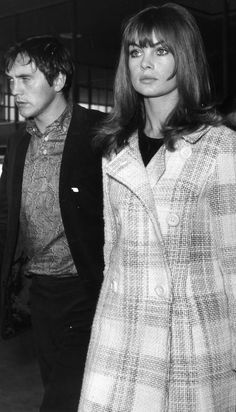 a man and woman are walking together in an airport, one is wearing a coat