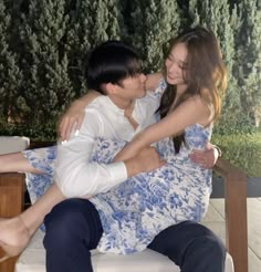 a man and woman sitting on top of a white chair next to eachother