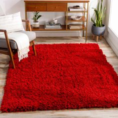 a living room with a red rug on the floor next to a chair and table